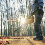 Mann mit Laubsauger im Herbst